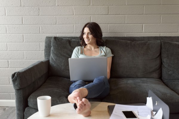Caucasian woman sitting on sofa using laptop