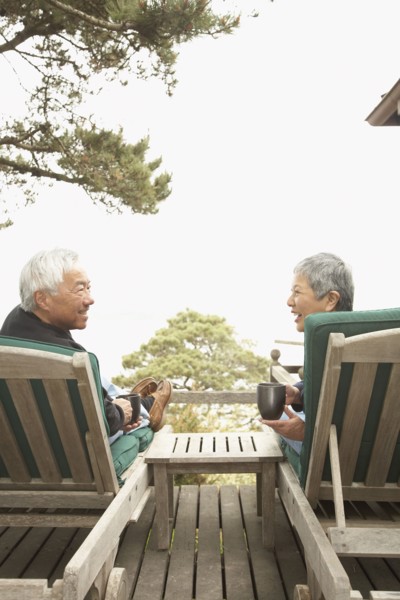 Senior Asian couple drinking coffee and talking outdoors