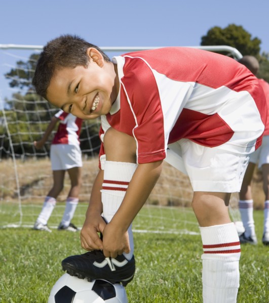 Mixed Race boy tying soccer shoe