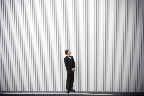 Uncertain groom standing near wall