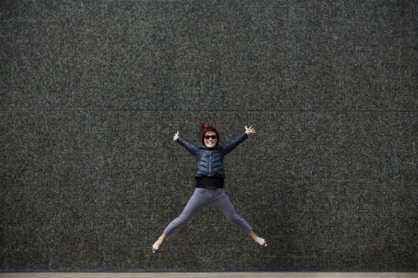 Korean woman jumping on city sidewalk