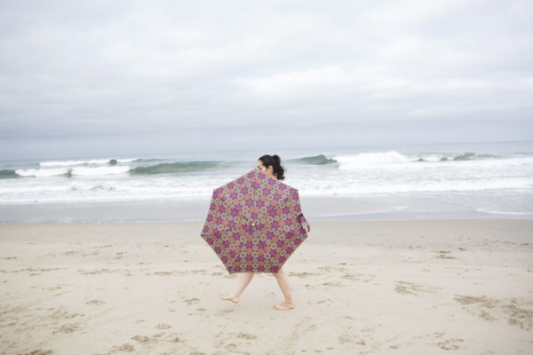 Woman walking with umbrella on beach