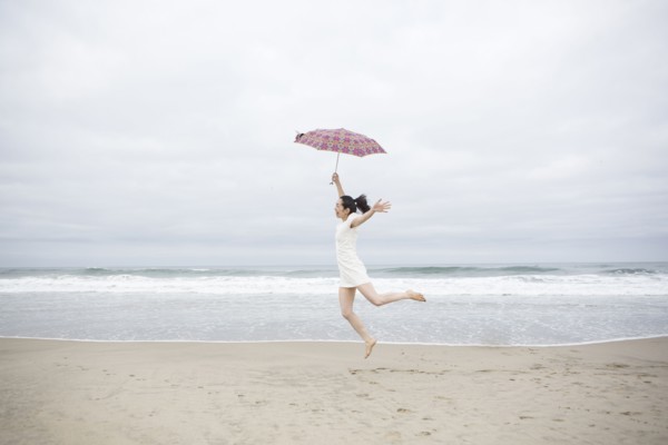 Woman playing with umbrella on beach