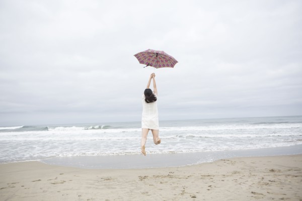 Woman playing with umbrella on beach