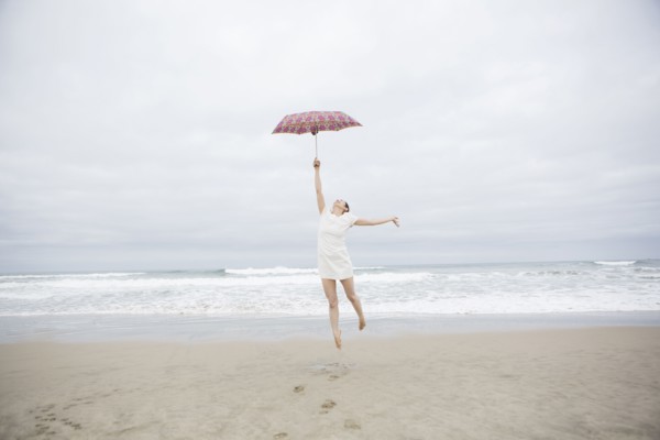 Woman playing with umbrella on beach