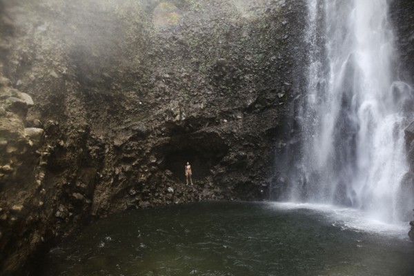 Mixed Race woman standing near waterfall pool