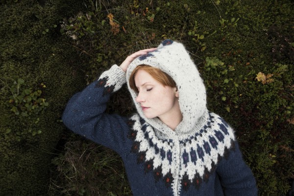 Caucasian woman wearing sweater laying on moss