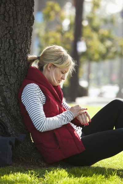 Caucasian woman leaning against tree in park