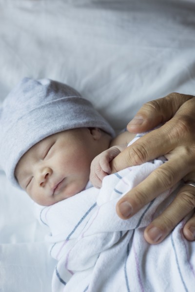 Close up of newborn baby holding finger of father