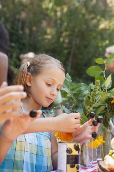 Girl picking flowers and berries in backyard