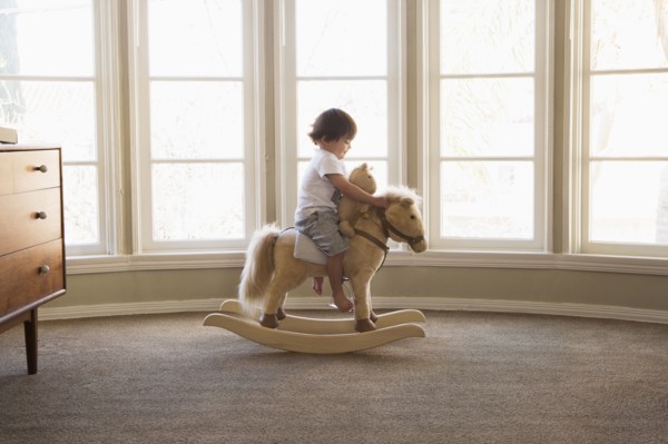 Mixed Race boy sitting on rocking horse near window