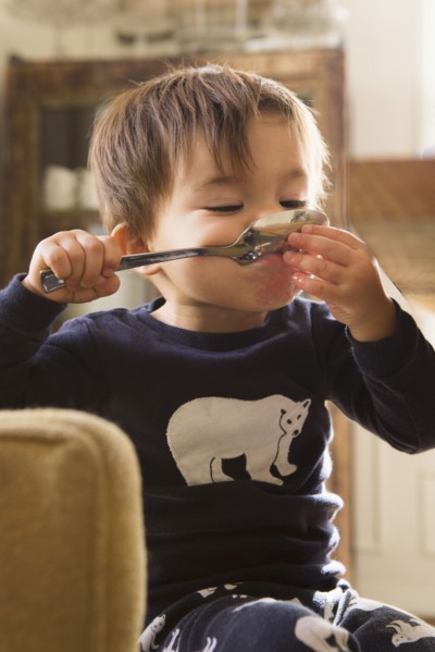 Mixed Race boy holding spoon in mouth
