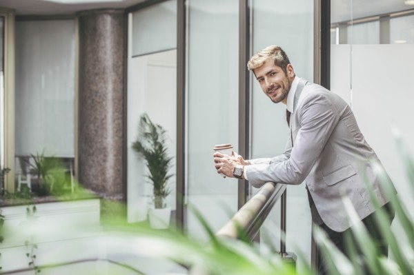 Caucasian businessman drinking coffee on office balcony