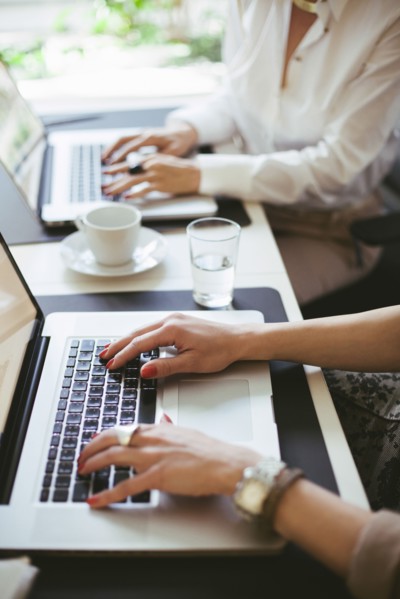 Caucasian businesswomen working at laptops at desk