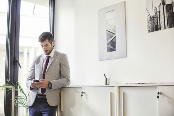 Caucasian businessman using cell phone in office