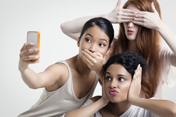 Women posing and taking cell phone selfie