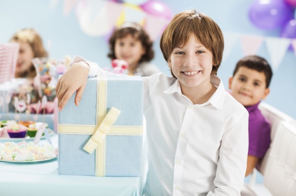 Boy smiling with wrapped gift at birthday party