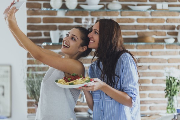 Caucasian women taking selfie in kitchen with pasta