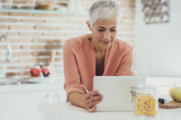 Older Caucasian woman using digital tablet in kitchen