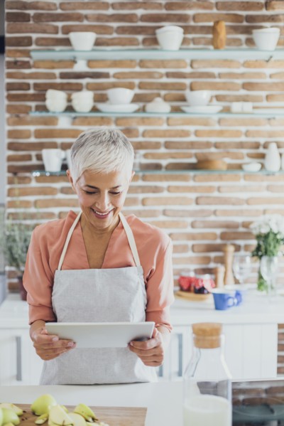 Older Caucasian woman using digital tablet in kitchen