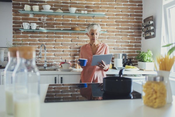 Older Caucasian woman using digital tablet in kitchen