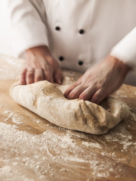 Hands of baker kneading dough