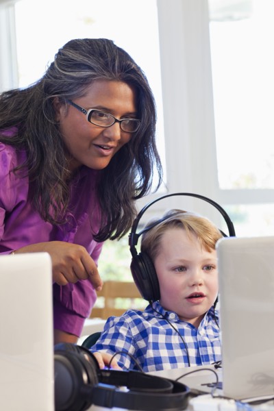 Teacher helping student using laptop