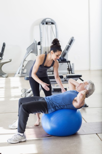 Older Hispanic man working with trainer in gym