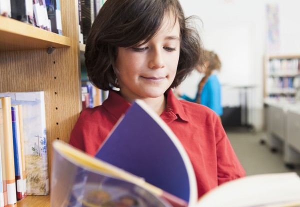Caucasian boy reading book in library