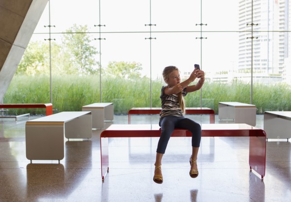 Caucasian girl taking self-portrait in lobby