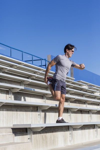 Hispanic athlete stretching on bleachers