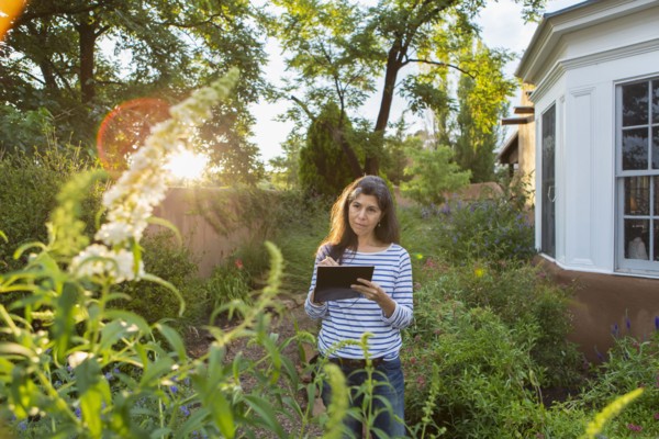 Hispanic woman sketching flowers in garden