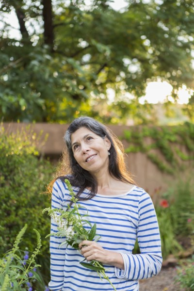 Hispanic woman holding flowers in garden