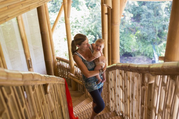 Caucasian mother carrying baby up stairs