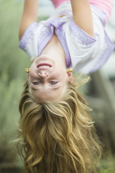 Caucasian girl hanging upside down outdoors