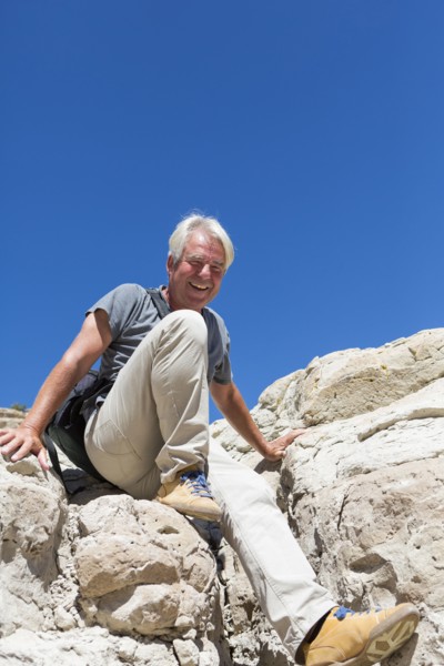 Older Caucasian man climbing rock formations
