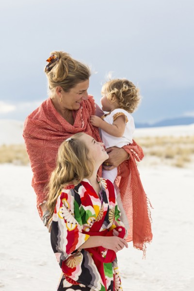 Caucasian mother and children laughing on sand dune