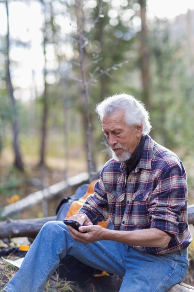Caucasian hiker using cell phone in forest