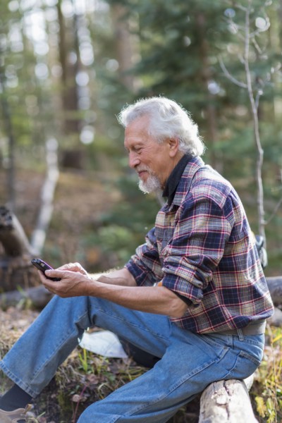 Caucasian hiker using cell phone in forest