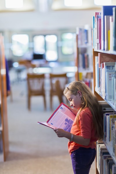 Caucasian student reading book in library