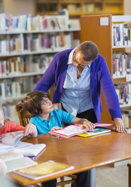 Teacher helping student in library