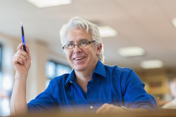 Hispanic adult student raising his hand in class