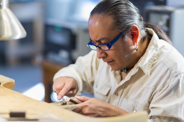 Close up of Native American jeweler working in studio