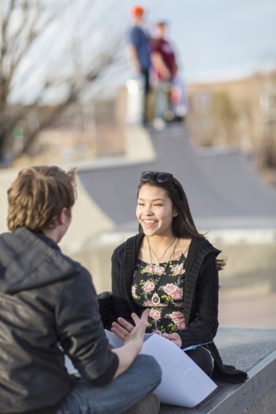 Teenage couple talking at skateboard park