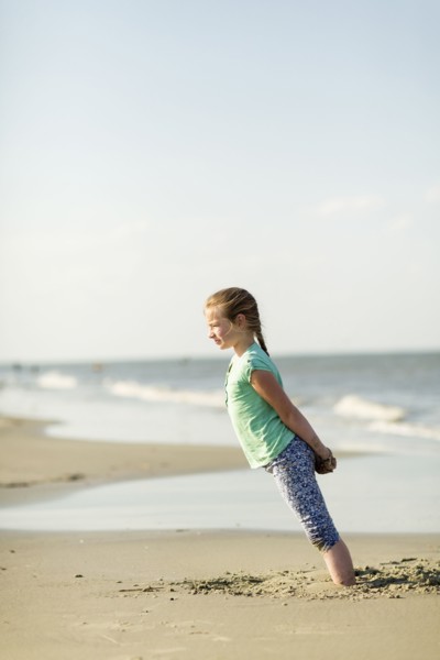Caucasian girl leaning in sand on beach