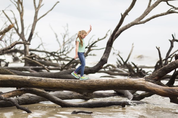 Caucasian girl walking on driftwood tree