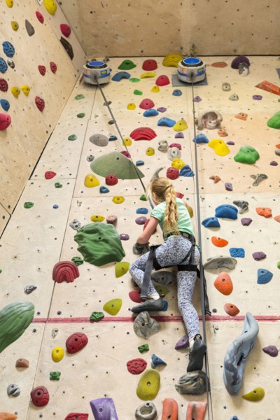 Caucasian girl climbing rock wall indoors