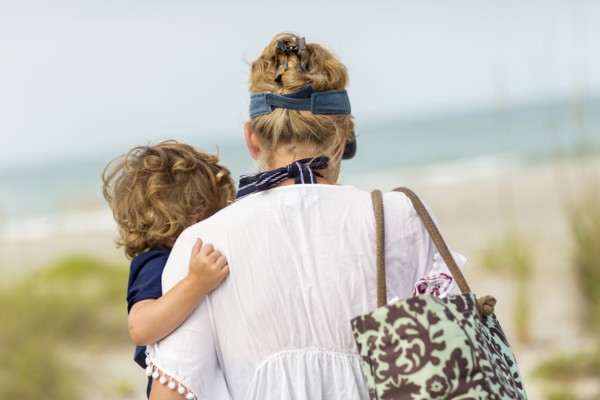 Caucasian mother carrying baby son on beach