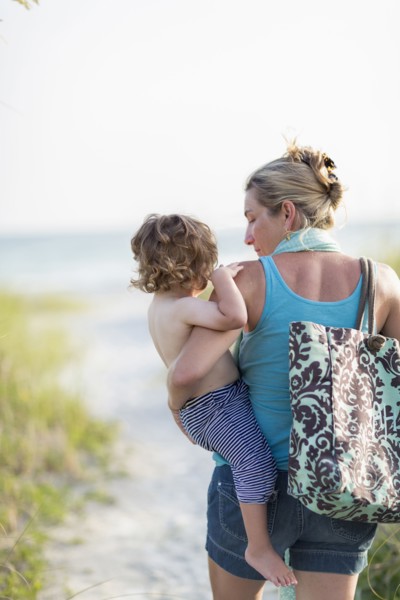 Caucasian mother carrying baby son on beach