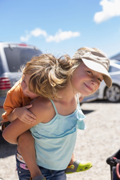 Caucasian girl carrying brother piggyback